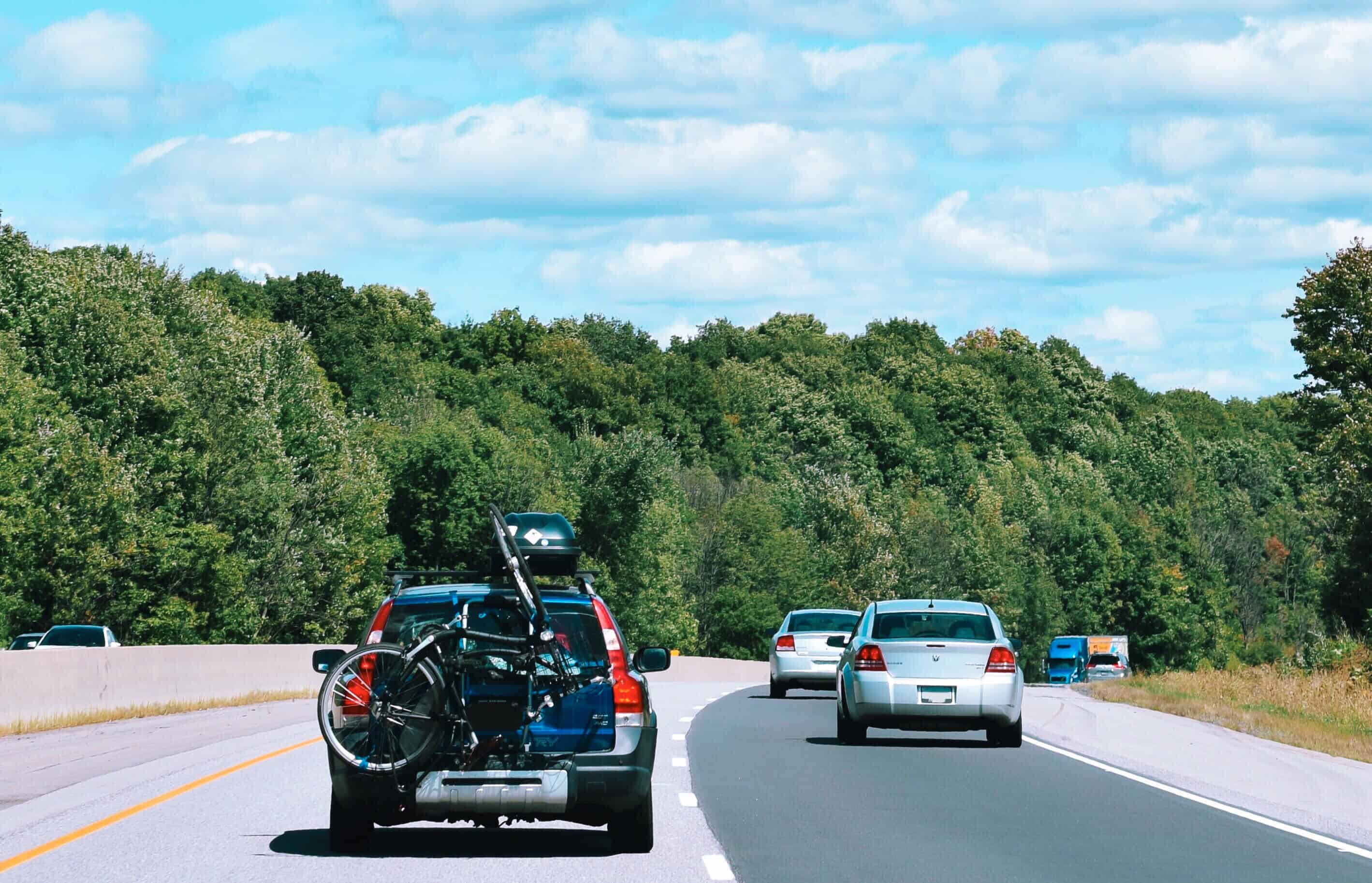 a-car-with-a-bike-attached-in-the-back-driving-on--LSNVFQJ (1)